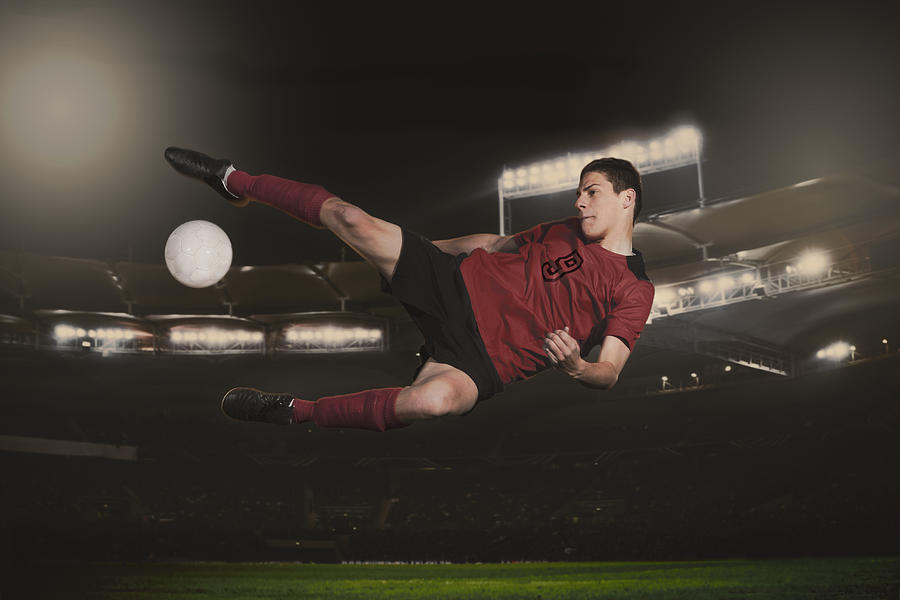 Full length of soccer player kicking ball during match Photograph by Adam Burn
