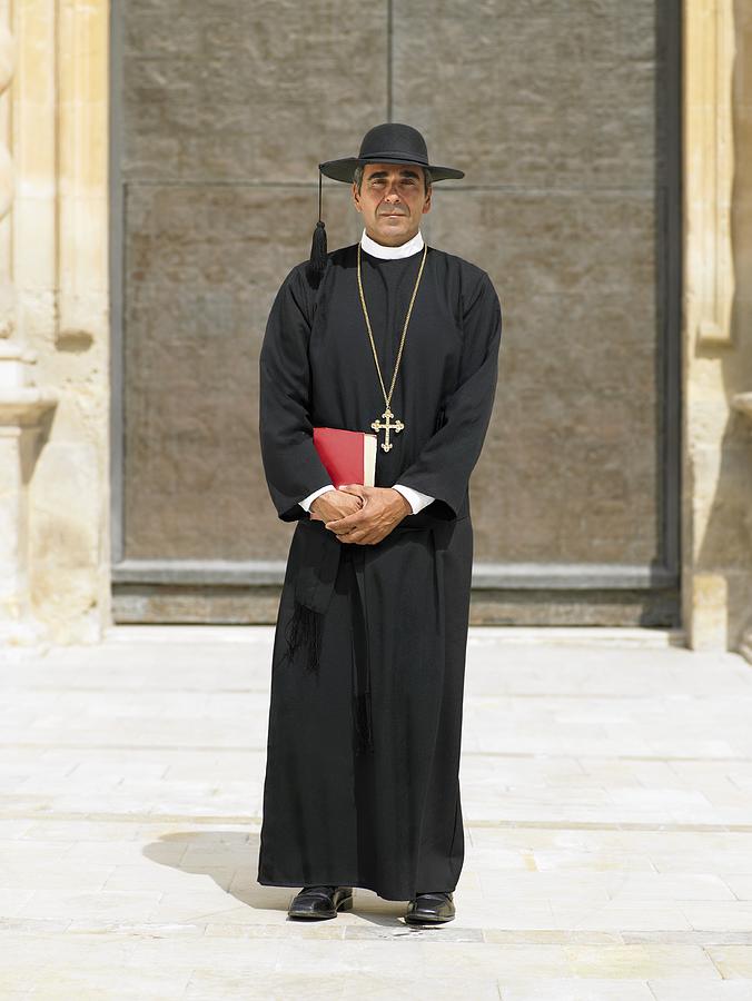 Full length portrait of priest by ornate door, Alicante, Spain, Photograph by Dev Carr
