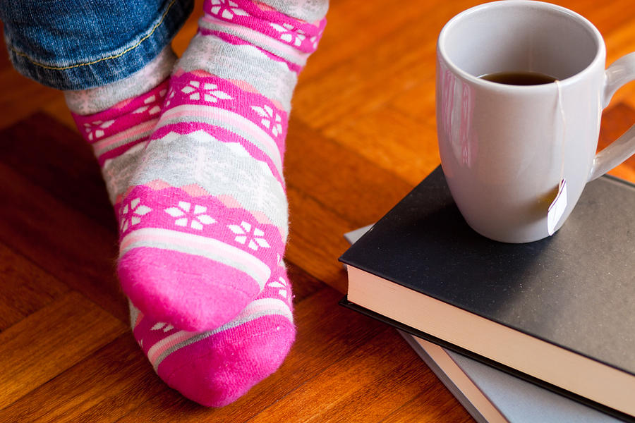 Funny colored socks with cup of tea and books. Photograph by Zianlob
