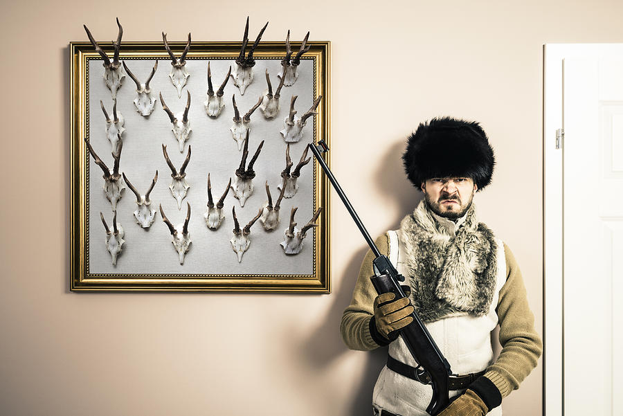 Funny portrait of serious hunter man with shotgun and antlers Photograph by Domin_domin