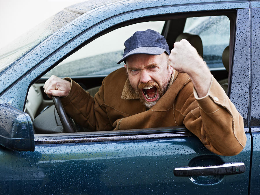 Furious male driver shakes his fist out of car window Photograph by RapidEye