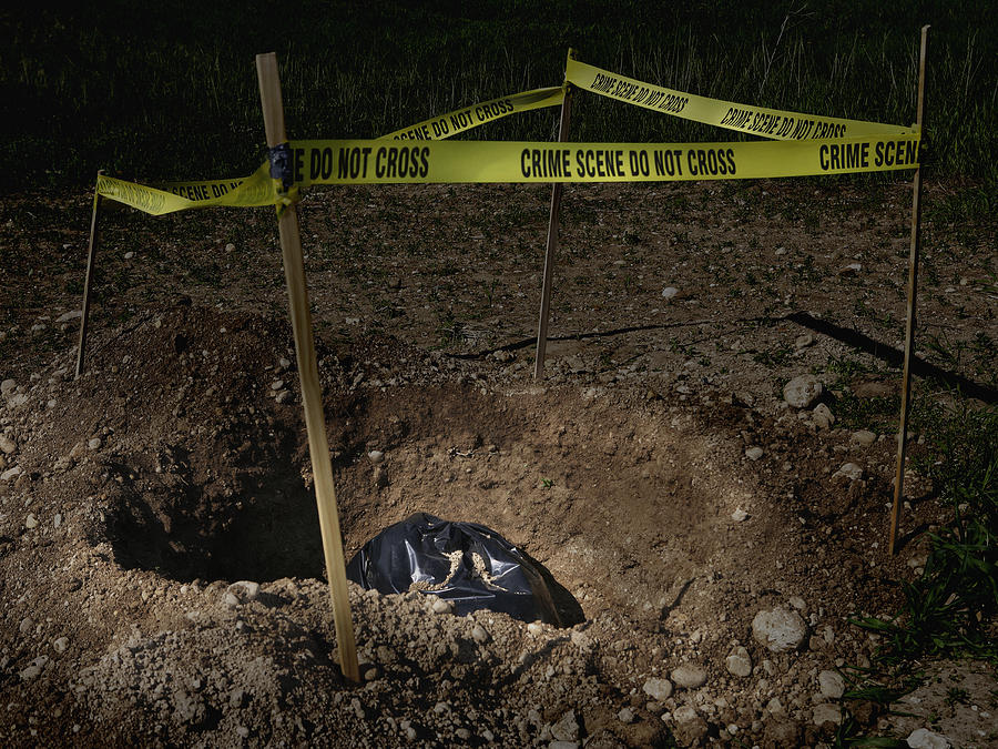 Garbage bag in dug hole with crime scene tape Photograph by Steven Puetzer