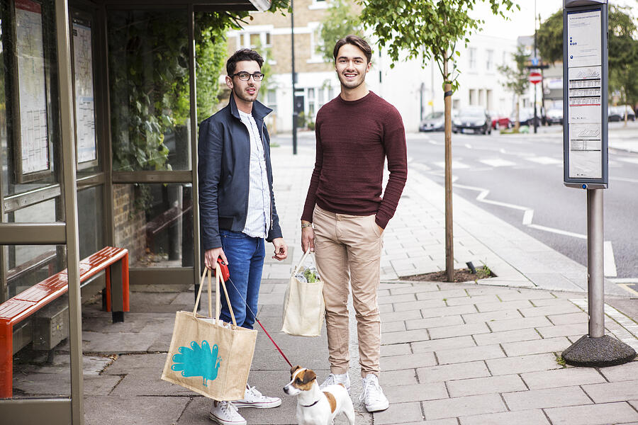 Gay Couple With Dog And Shopping Waiting For Bus. Photograph by Betsie Van Der Meer
