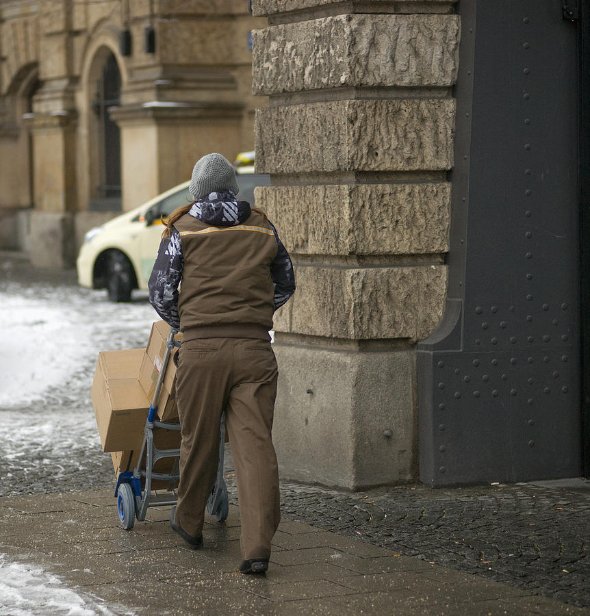 Germany, Bavaria, Munich, View Of Delivery Man Pushing Cart With Boxes Photograph by Kypros