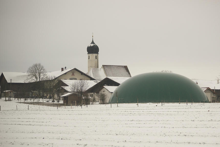 Germany, Bavaria, View Of Snow Covered Farmland With Plastic Manure Storage Dome, Church In Background Photograph by Kypros