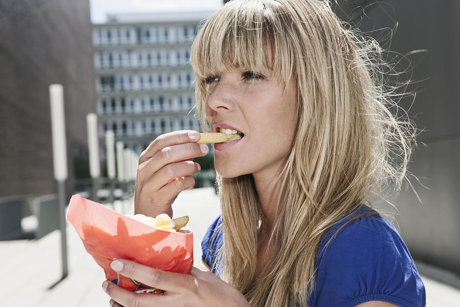 Germany, Cologne, Young woman eating french fries Photograph by Westend61