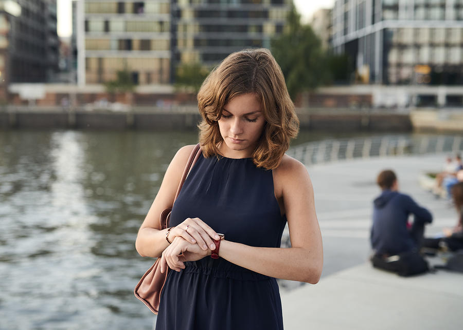 Germany, Hamburg, Young woman looking at watch Photograph by Westend61