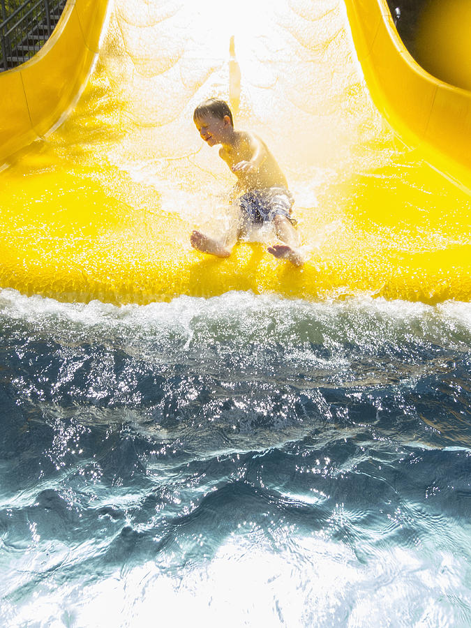 Germany,Thuringia, Boy (6-7) having fun on water slide Photograph by Johannes Kroemer