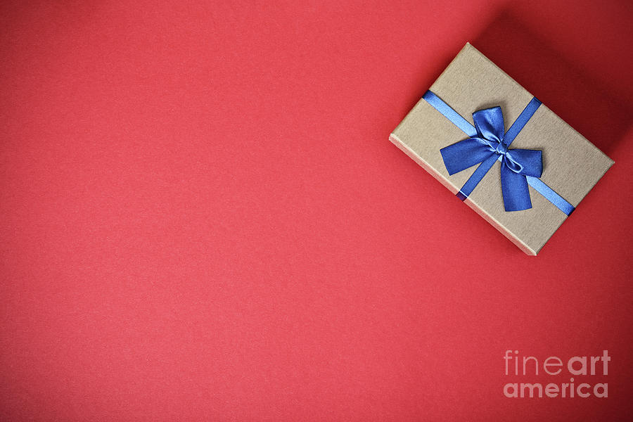 Gift box with a blue bow on red background Photograph by Mendelex Photography