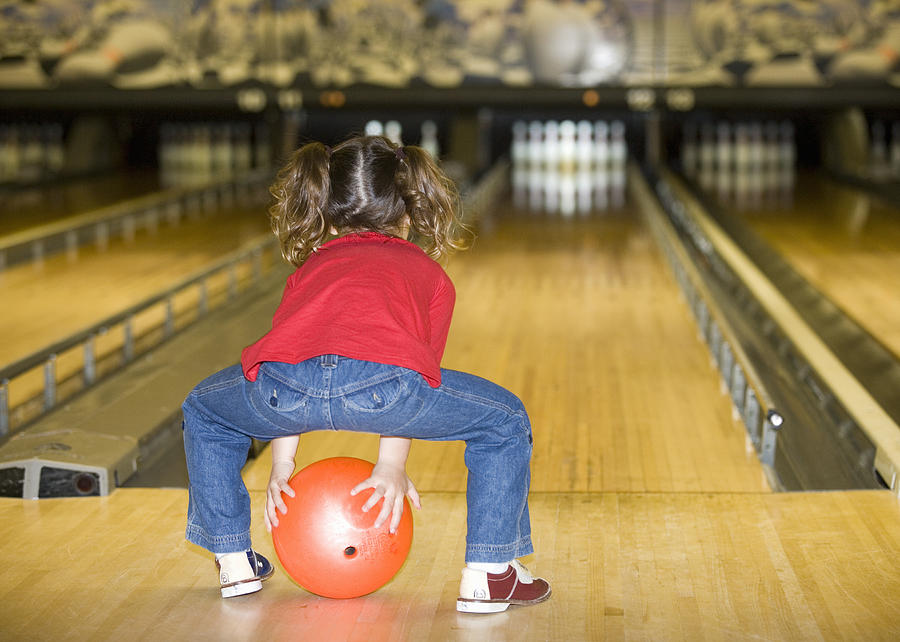 Girl (3-4) bowling, rear view Photograph by Jonathan Kirn