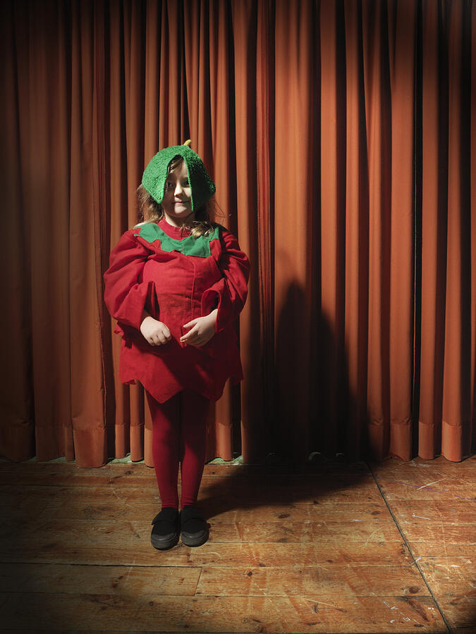 Girl (4-6) standing on stage wearing tomato costume, portrait Photograph by Colin Hawkins