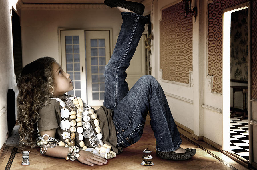 Girl (6-7 years) lying in miniature room, side view Photograph by Regine Mahaux