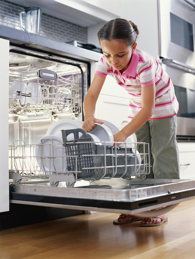 Girl (6-8) unloading dishwasher, low angle view Photograph by Kraig Scarbinsky