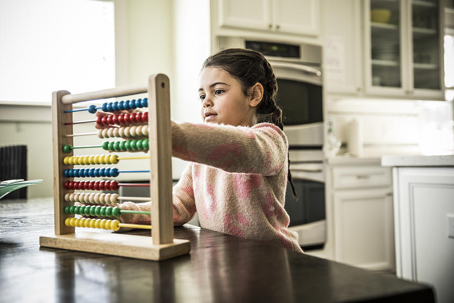 Girl (7 yrs) using abacus Photograph by MoMo Productions