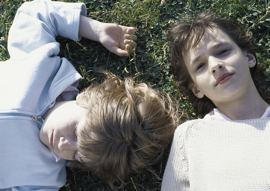 Girl and boy lying on grass Photograph by Laurence Mouton