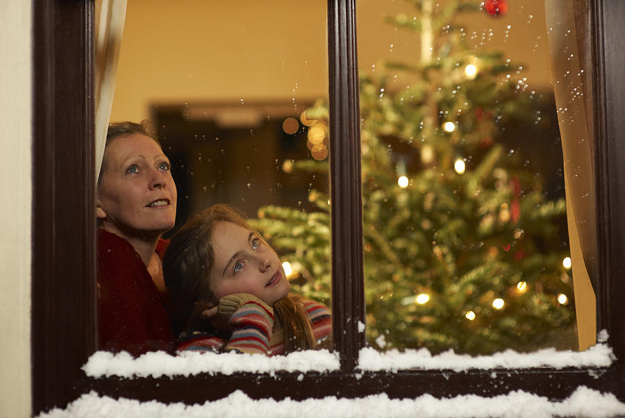 Girl and mother gazing out of window at christmas. Photograph by Dougal Waters