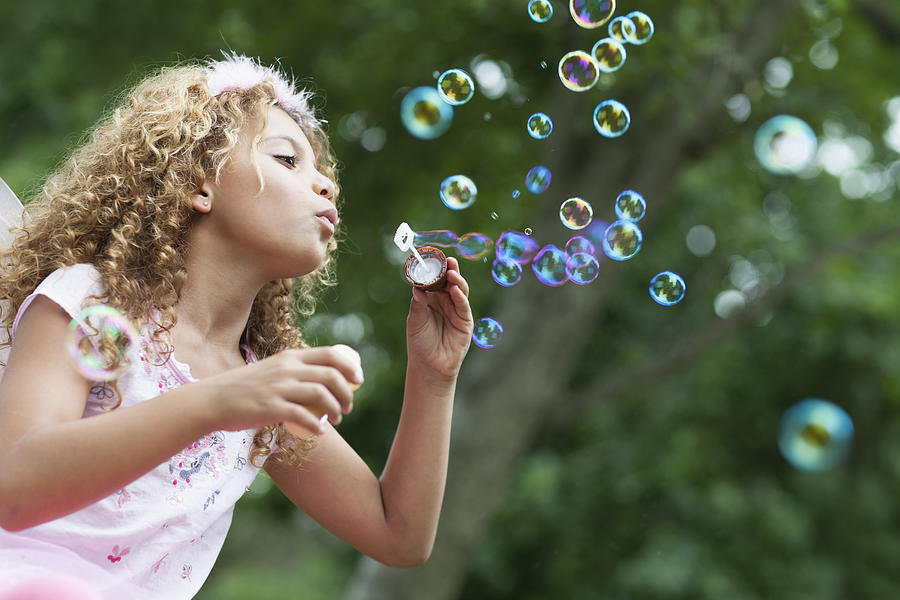 Girl blowing bubbles outdoors Photograph by Cultura RM Exclusive/Hybrid Images
