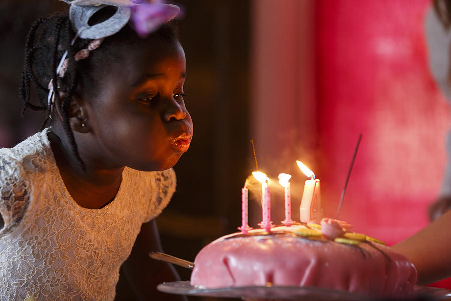 Girl blowing out candles on cake Photograph by Anders Andersson