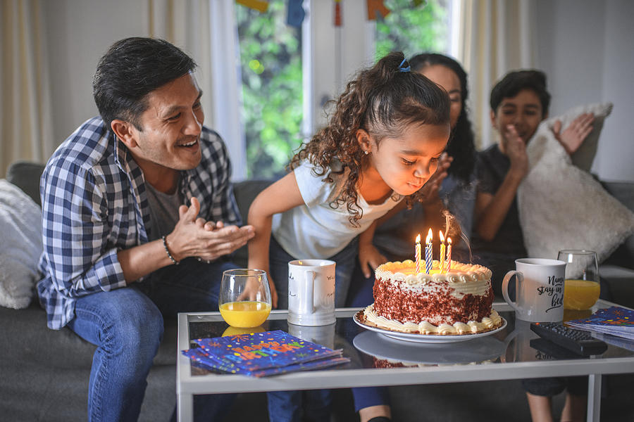 Girl celebrating birthday with family at home Photograph by AzmanL