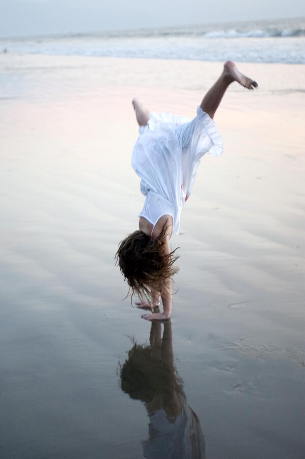 Girl doing a cartwheel on the beach Photograph by Design Pics/Keith Levit