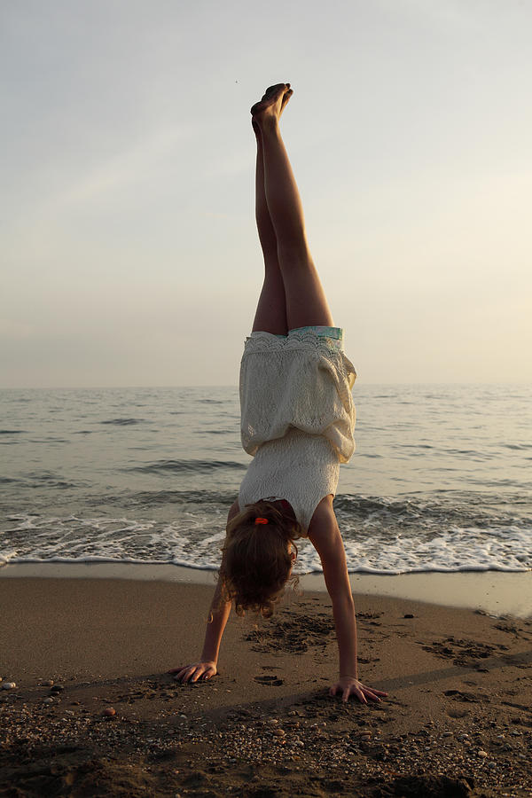 Girl doing a handstand at the beach Photograph by Aitor Diago