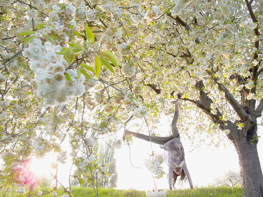 Girl doing cartwheels under flowering tree Photograph by Tom Merton