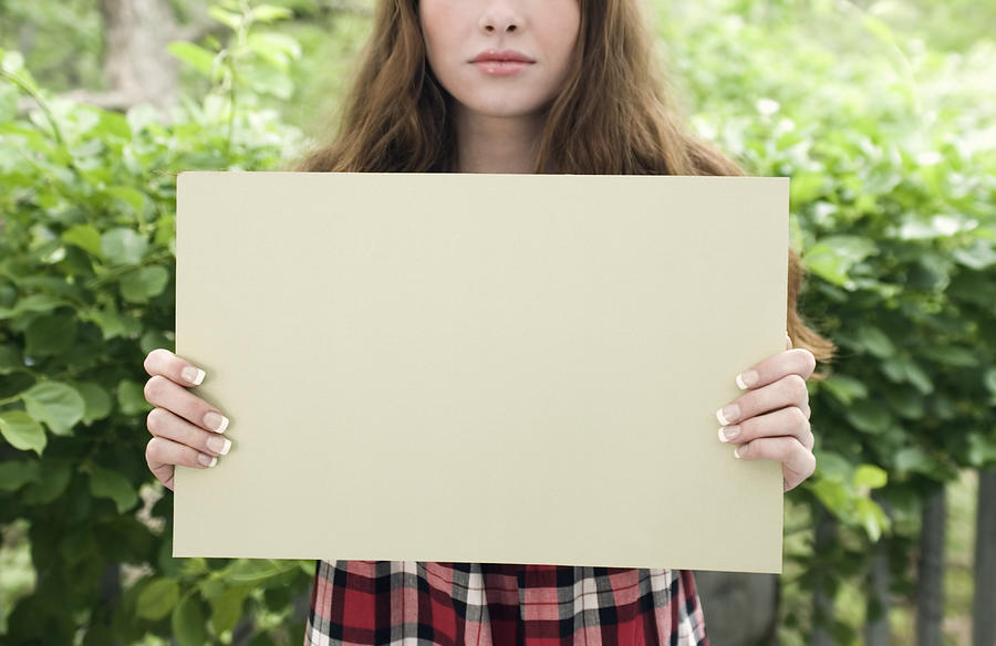 Girl early 20s holding blank sign expressionless  Photograph by Steve Wisbauer