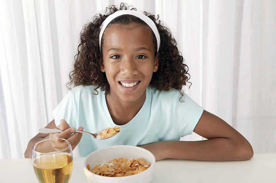 Girl eating breakfast at home Photograph by Comstock Images