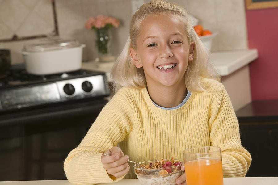 Girl eating cereal Photograph by Comstock Images
