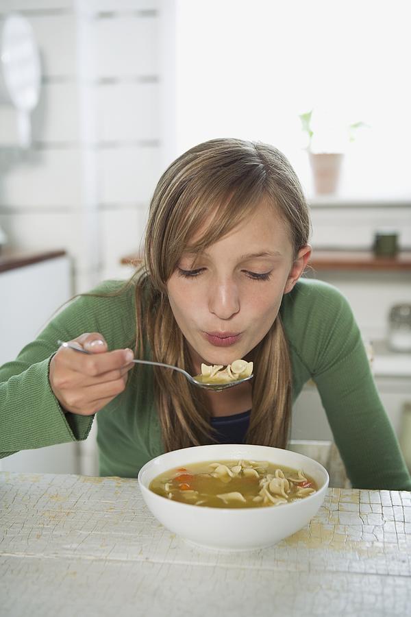 Girl eating chicken noodle soup Photograph by Fancy/Veer/Corbis