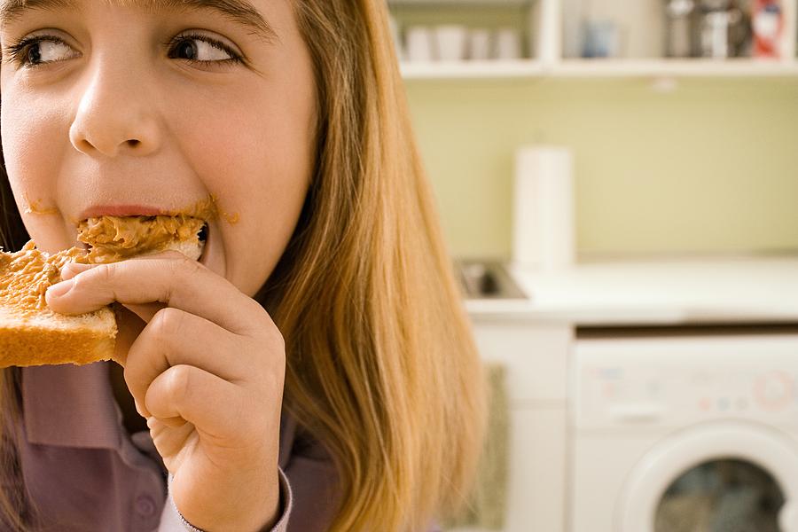 Girl eating toast in kitchen Photograph by Image Source