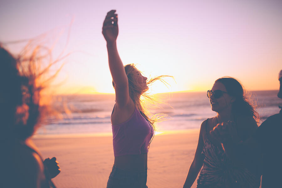 Girl feeling free against a beach sunset with friends Photograph by Wundervisuals