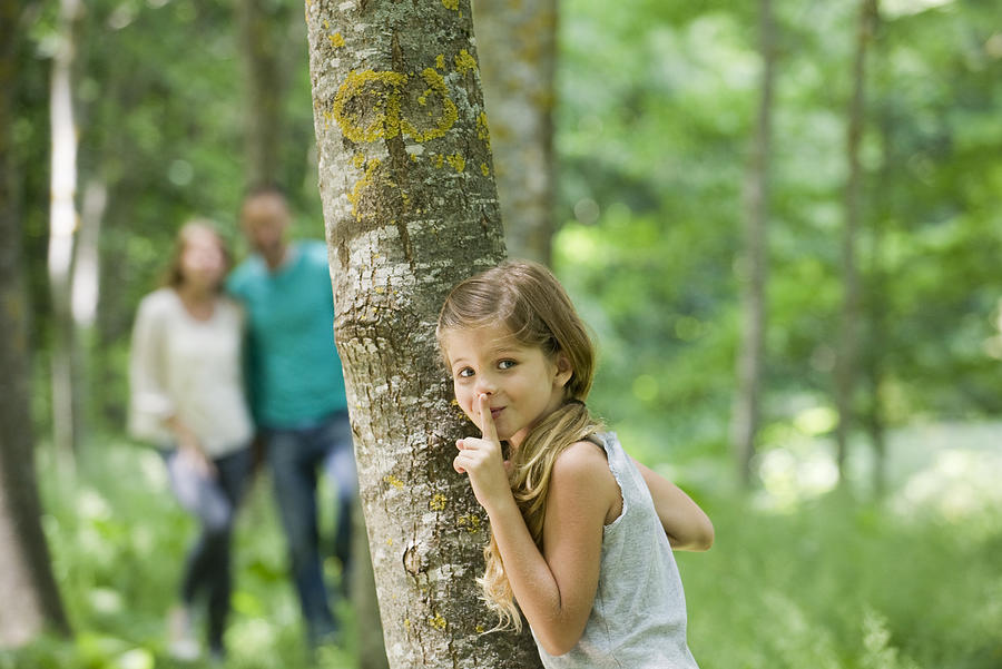 Girl hiding behind tree with finger on lips Photograph by ZenShui/Eric Audras