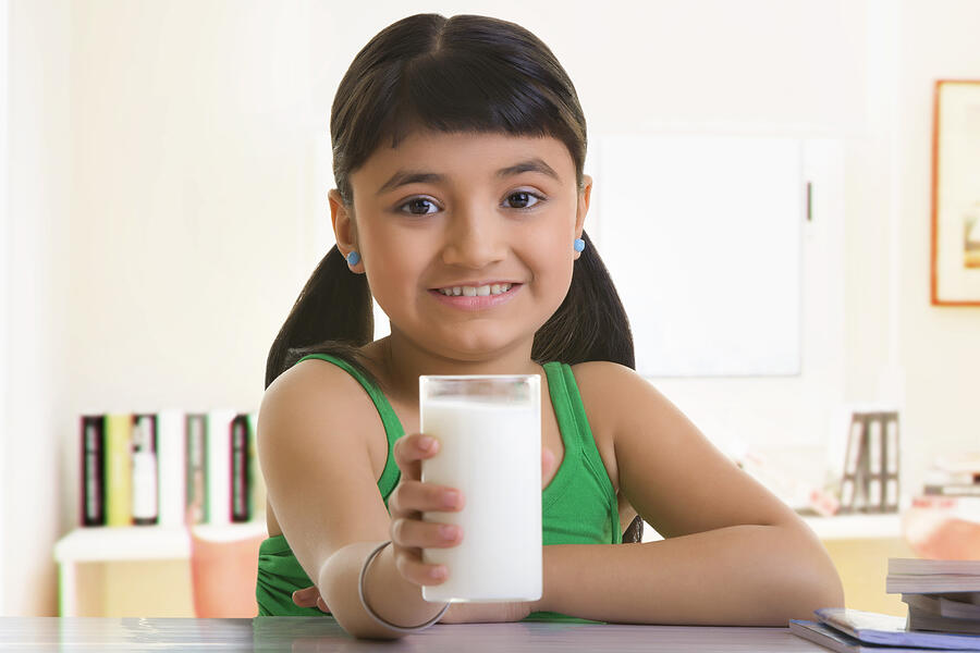 Girl holding a glass of milk Photograph by IndiaPix/IndiaPicture
