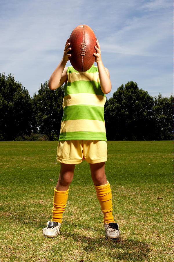 Girl holding football in front of her face Photograph by Cameron Spencer