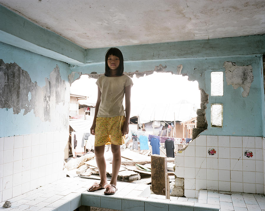 Girl in damaged kitchen following typhoon Photograph by Michael Hall