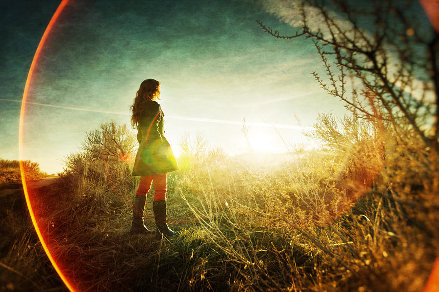 Girl in field looking at sunset, lens flare rings Photograph by Anna Gorin