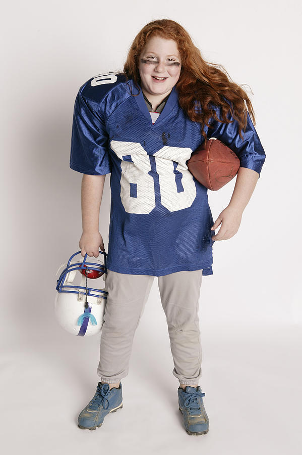 Girl in football player costume Photograph by Comstock Images