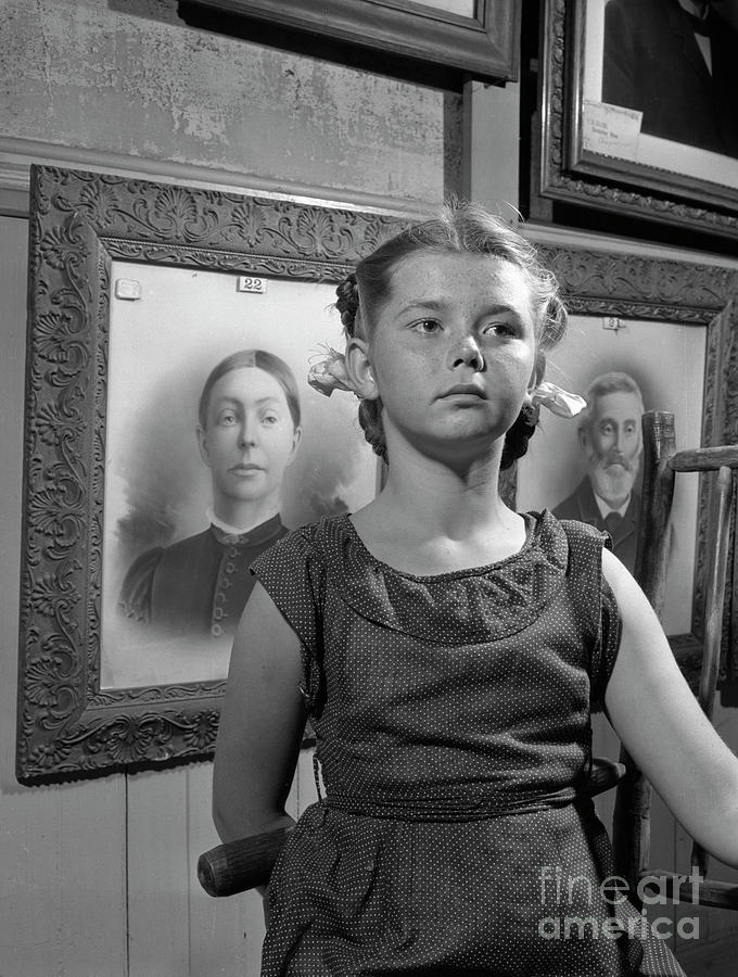 Girl in front of family portraits 1946 Photograph by The Harrington Collection