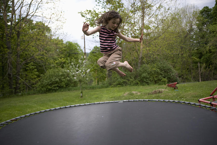 Girl jumping on trampoline Photograph by Jeff Randall