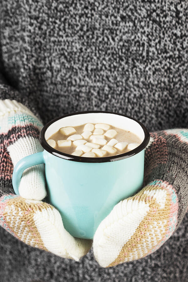 Girl keeps a mug of cocoa with marshmallows in mittens Photograph by Matucha
