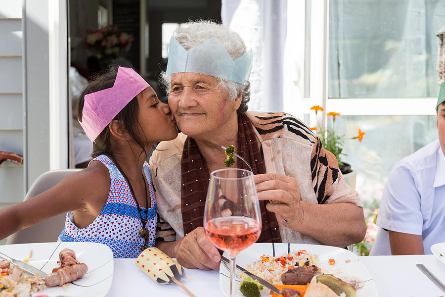Girl kisses grandma at outdoor Christmas lunch Photograph by Jessie Casson