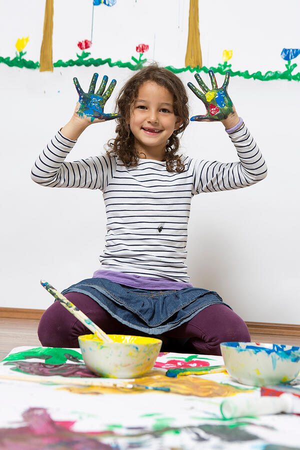 Girl kneeling on floor with painted hands Photograph by Severin Schweiger