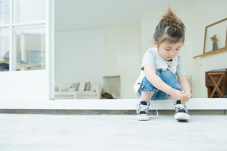 Girl learning to tie her shoelaces Photograph by Image Source
