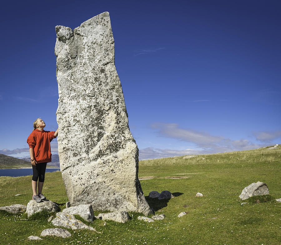 Girl looking up at ancient stone monolith Outer Hebrides Scotland Photograph by fotoVoyager