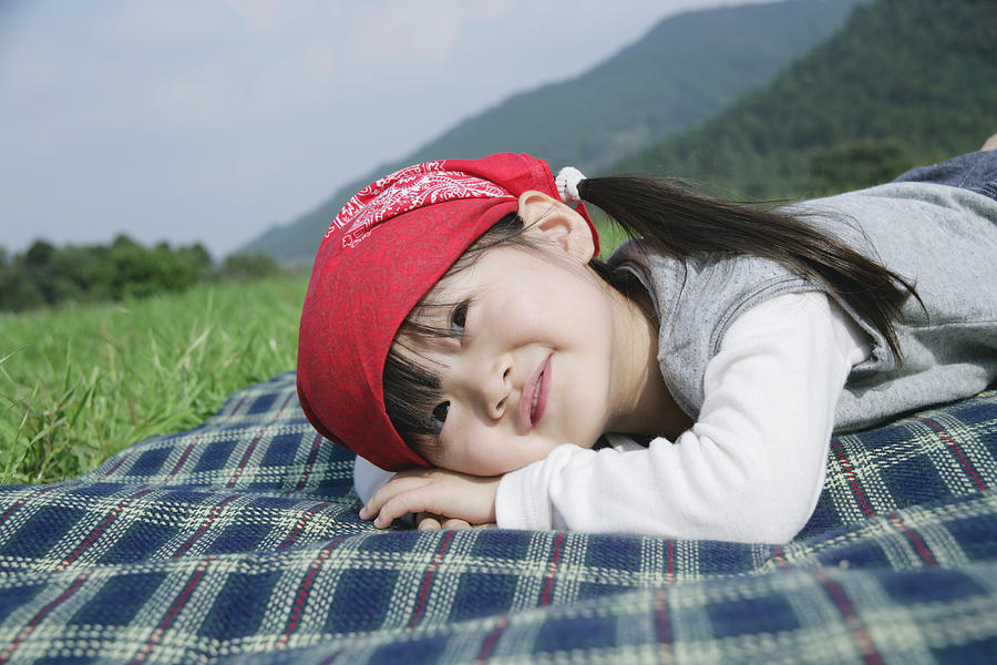 Girl lying down on picnic blanket Photograph by Koki Iino