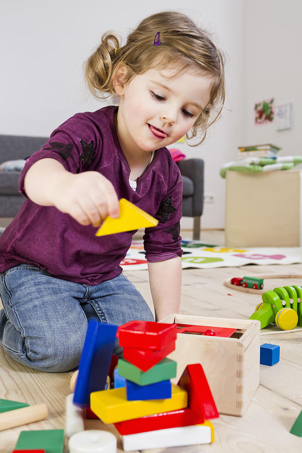 Girl playing with building blocks at home Photograph by Emely