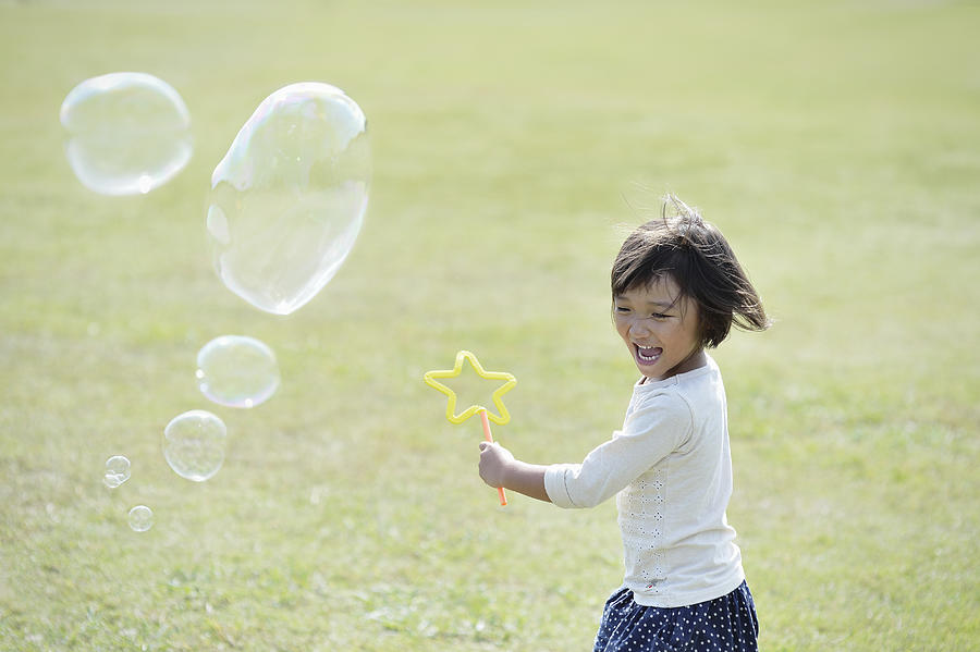 Girl playing with soap bubbles in green Photograph by Yagi Studio