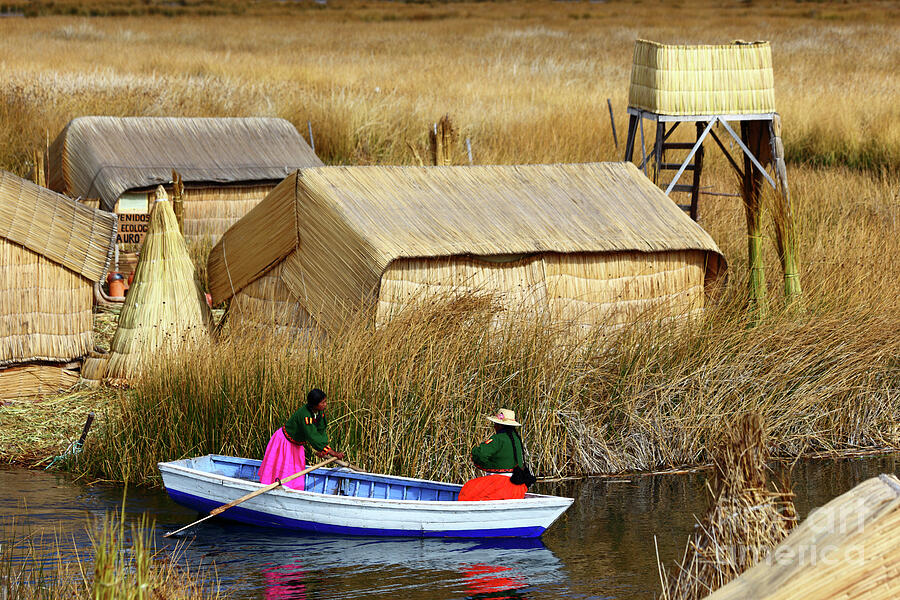 Landscape Photograph - Girl rowing a boat past reed houses Uros Islands Lake Titicaca Peru by James Brunker
