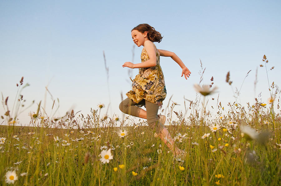 Girl running in field of flowers Photograph by Simon Potter